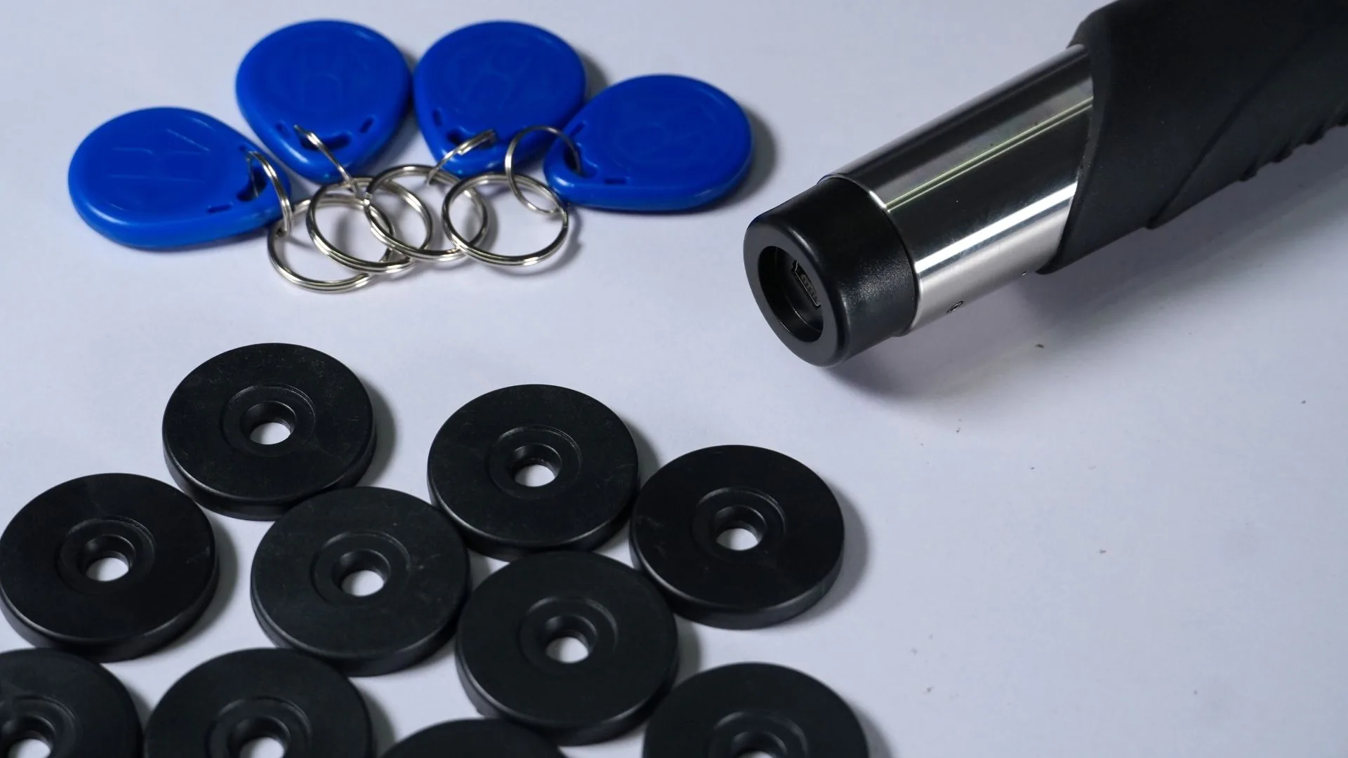 Sistema de control de rondas 5 Lector portátil del control de rondas junto a sus llaveros azules y sus puntos de control negros.