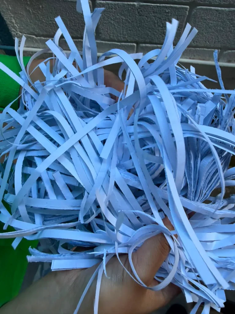 Papel triturado en tiras por la destructora HSM PURE 530, sostenido en la mano.