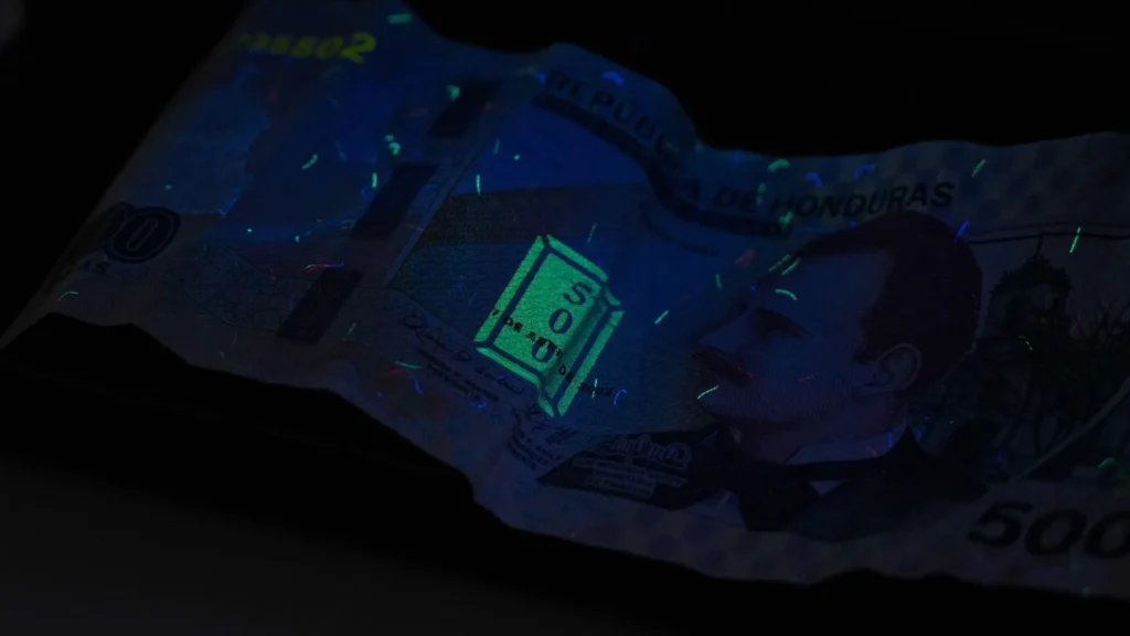 Lámpara UV Volteck 12 Billete de 500 lempiras bajo la luz ultravioleta, con sus fibras y marcas de seguridad fluorescentes.