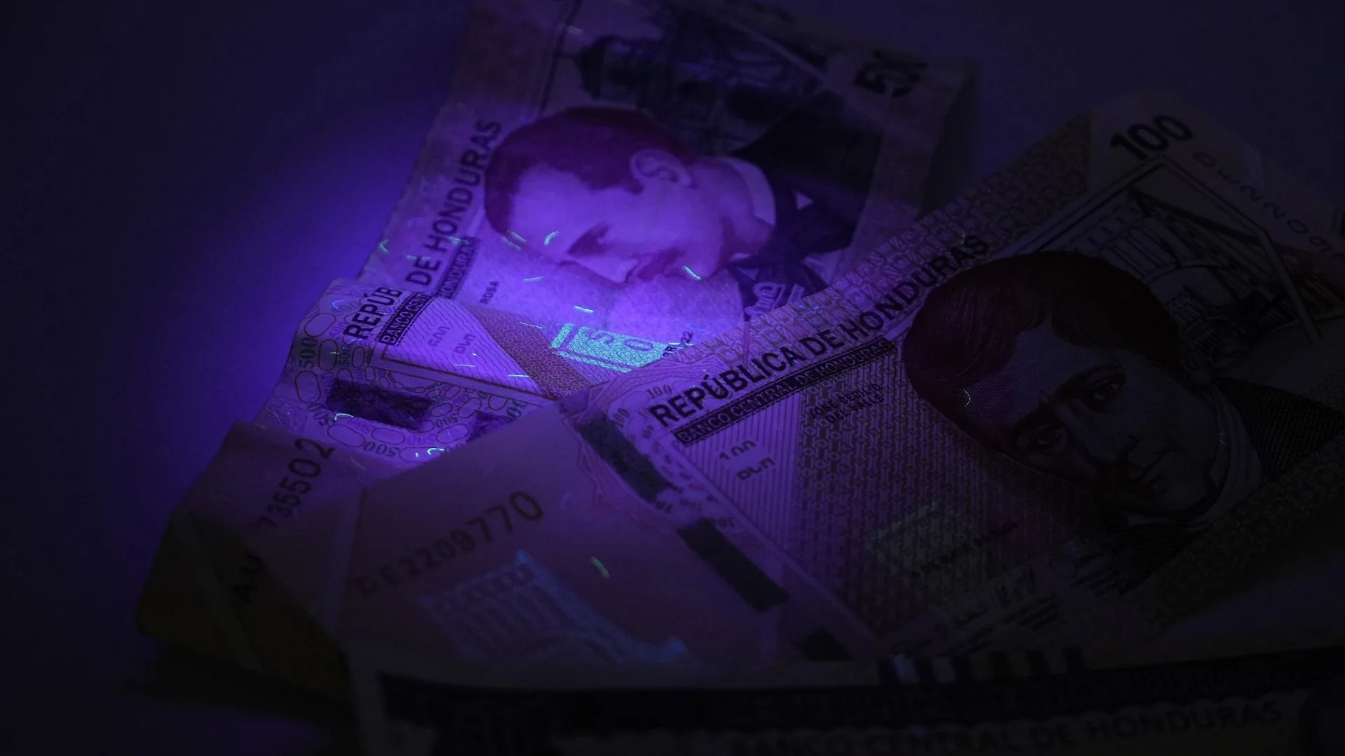 Billete de 100 lempiras revisado con la linterna UV para billetes.