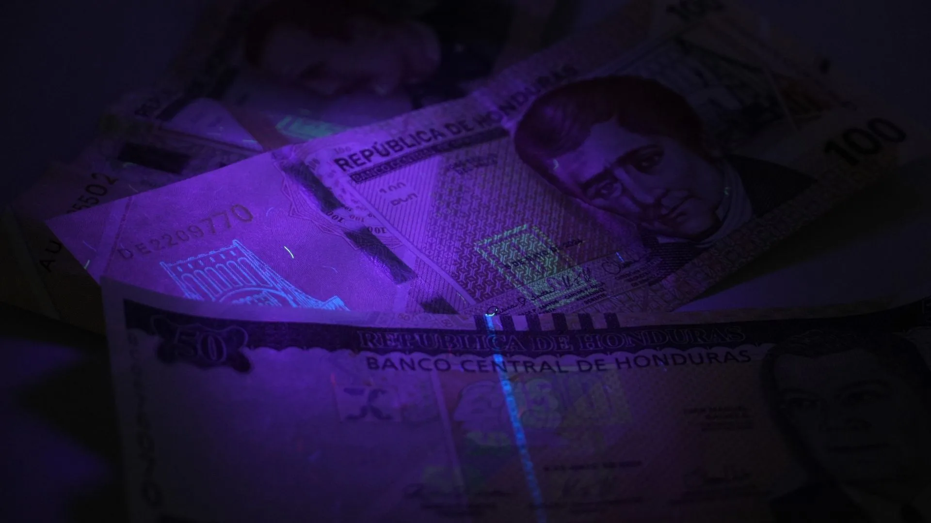 Marcas de seguridad de billetes de 50 y 100 lempiras bajo la linterna UV para billetes.