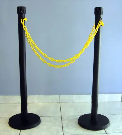 Dos postes negros con una cadena plástica amarilla colgada entre ellos.