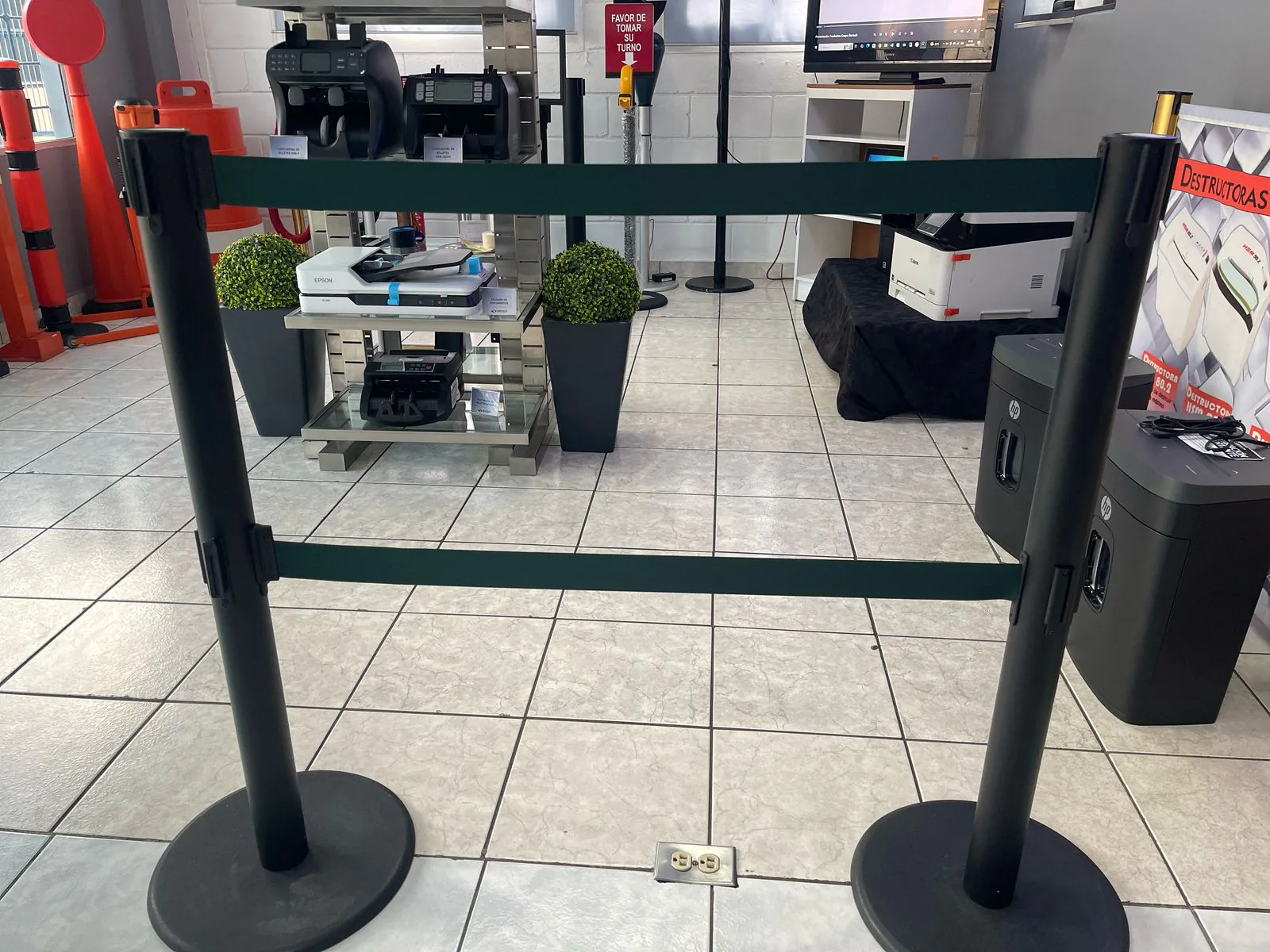 Dos postes de fila dual con su doble cinta verde tendida, con contadoras y trituradoras de fondo en la tienda de Bertech.