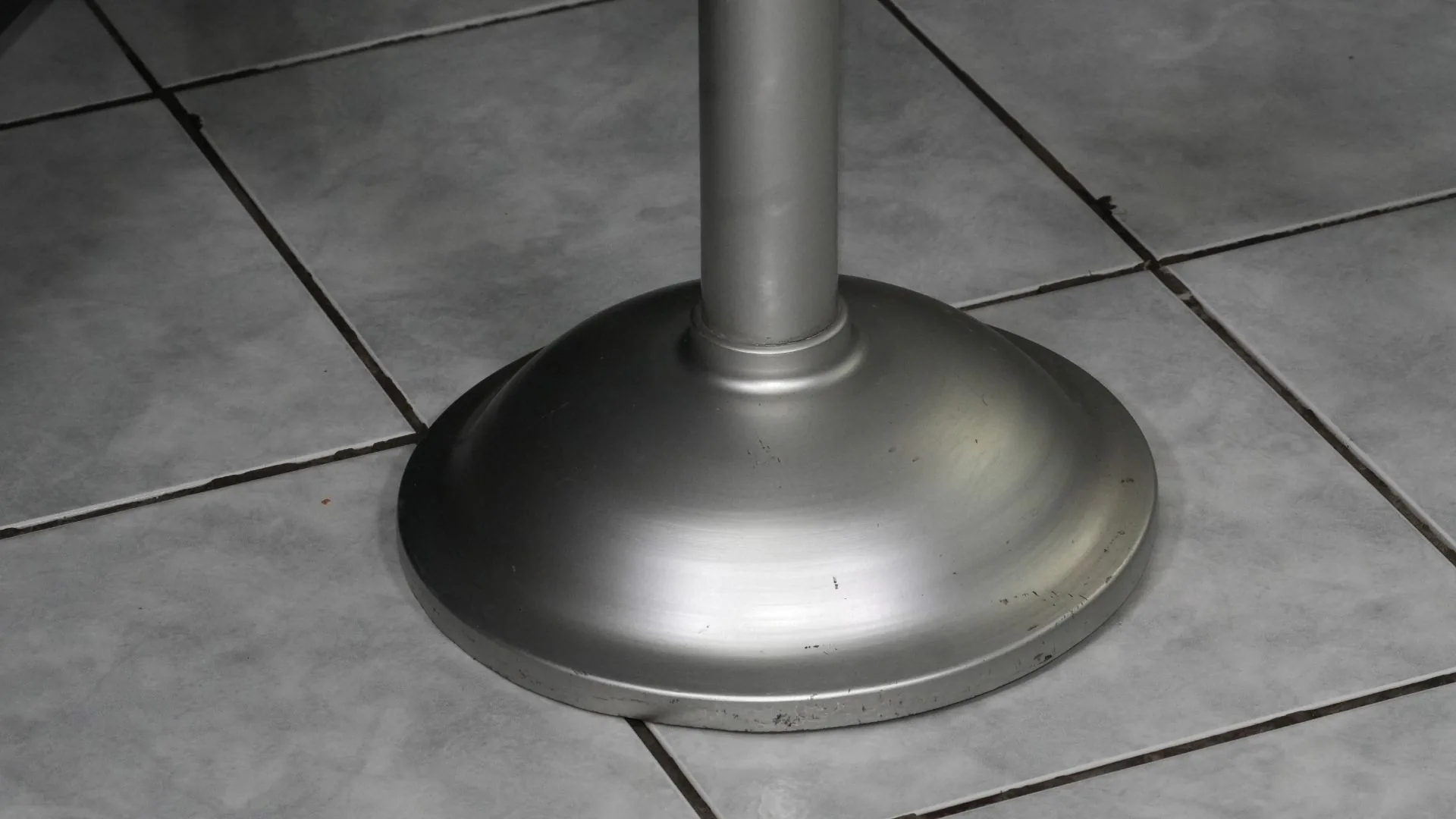 Base plateada de un poste de fila ejecutivo sobre piso de cerámica.