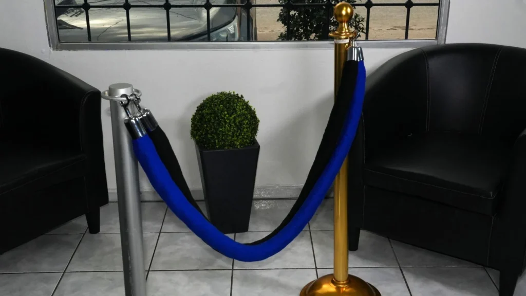 Postes de fila ejecutivos dorado y plateado unidos con cordones de terciopelo azul y negro, en la tienda de Bertech.