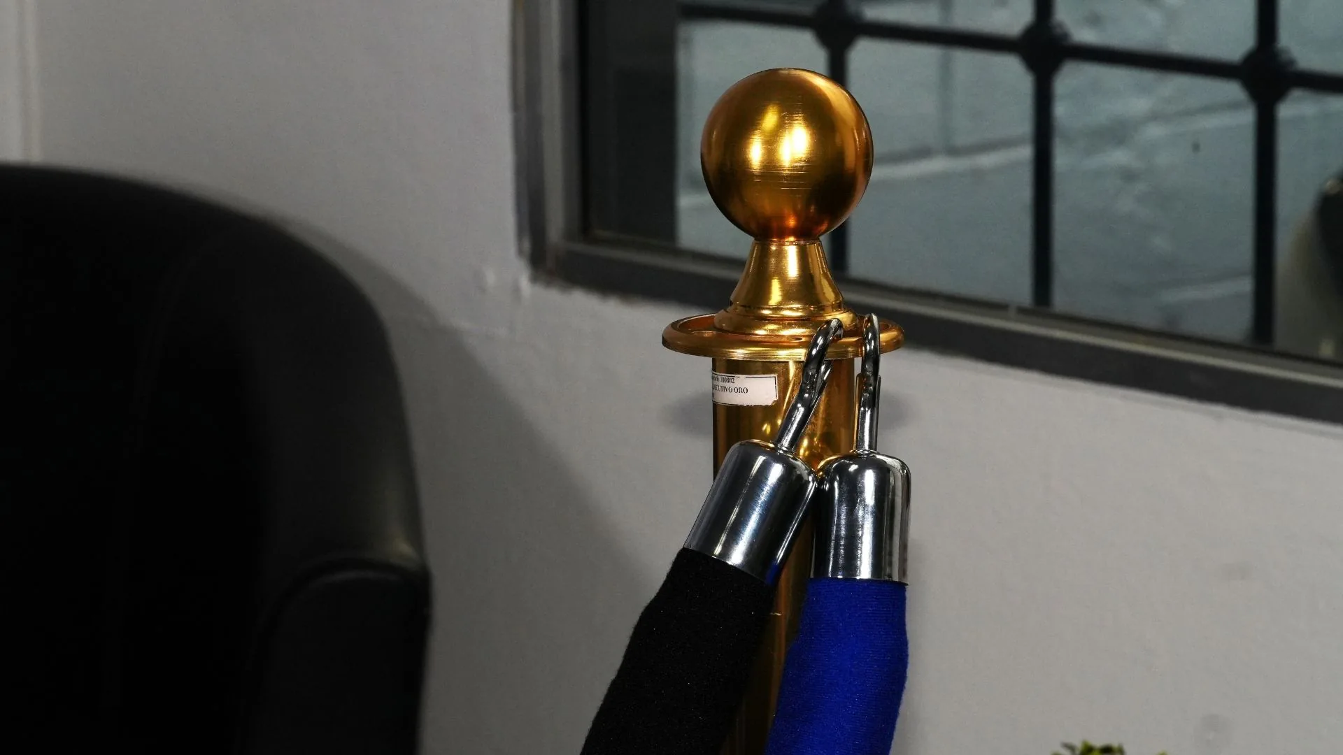 Dos cordones de terciopelo enganchados en un poste de fila ejecutivo dorado.