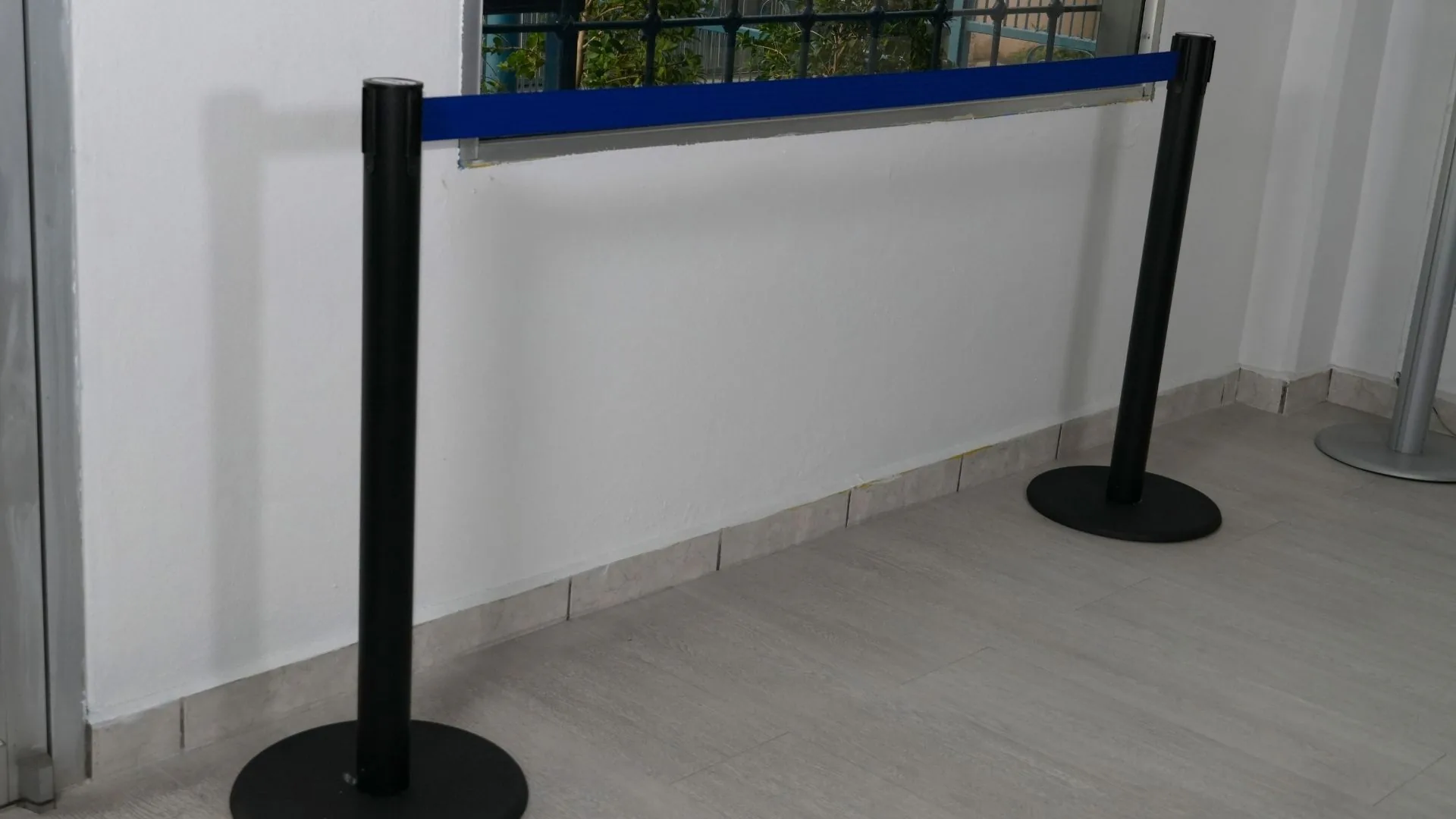 Dos postes de fila sencillos negros unidos por su cinta azul retráctil.