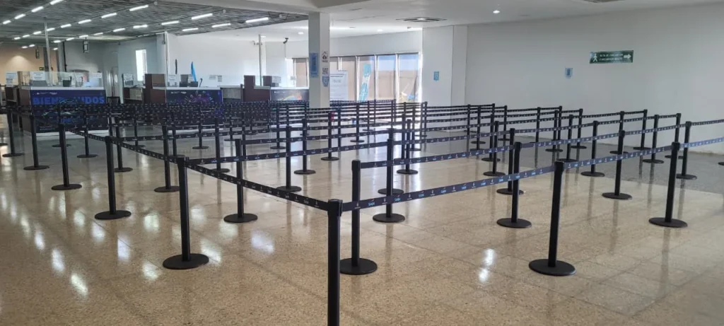 Filas en zigzag armadas con postes separadores frente a los mostradores del aeropuerto de Roatán.