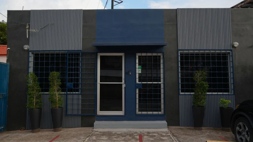 Fachada de la tienda de Bertech, con su puerta, sus ventanas enrejadas y sus plantas.